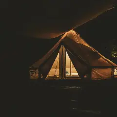 Nocne darmowe pola namiotowe. Oświetlony namiot tipi w ciemności, zapraszający do odpoczynku.