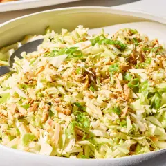 A refreshing Japanese cabbage recipe salad, topped with toasted almonds, sesame seeds, and green onions, served in a white bowl.