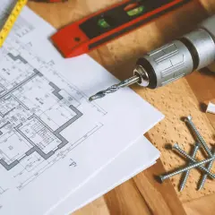 Plan de maison, mètre, vis, chevilles et perceuse de la marque Einhell, prêts pour le bricolage.