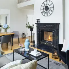 Elegancki portal kominkowy z czarnego marmuru, otoczony nowoczesnymi meblami i dekoracjami, tworzy przytulną atmosferę.