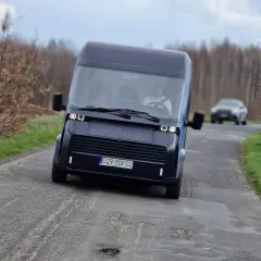 Nowoczesny polski samochód elektryczny przemierza wiejską drogę.