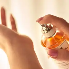 Dłoń rozpyla perfumy, tworząc subtelne stężenie zapachu.
