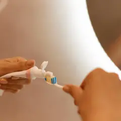 Dłonie nakładają pastę na szczoteczkę. Czy to RDA co to? Codzienna higiena jamy ustnej jest ważna.