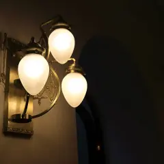 Elegancki kinkiet z trzema mlecznymi kloszami, rzucający ciepłe światło. Trudno ocenić ile lumenów na m2, ale tworzy przytulną atmosferę.