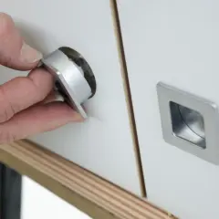 Mano insertando un tirador moderno en un mueble, renovando su aspecto. Ideal para cambiar tiradores mueble antiguo.