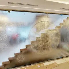 Witrażowe szkło strukturalne z motywem zodiaku i mandali. Schody widoczne przez matowe szkło.