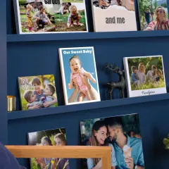 Schöne Fotowand Ideen mit Familienfotos auf blauen Regalen. Ein Baby, Kinder und Paare lächeln von den Bildern.