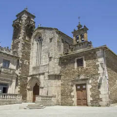 La iglesia de San Pedro de Lugo, con su imponente torre y fachada de piedra, se alza bajo un cielo azul.