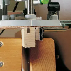 Utilisation d'un gabarit rainure défonceuse pour créer une entaille précise dans une pièce de bois.