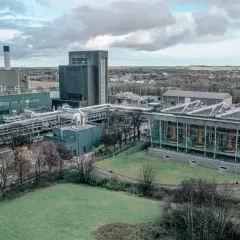 Vue aérienne de la distillerie Midleton, avec ses bâtiments industriels, ses cuves en cuivre visibles à travers une façade vitrée, et un paysage verdoyant en arrière-plan.