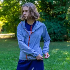 Kobieta w niebieskiej kurtce sportowej z pomarańczowymi zamkami. Taka membrana 10000 co to znaczy? To dobra ochrona przed deszczem i wiatrem podczas biegania.