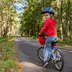 Chłopiec w kasku na rowerze na leśnej trasie rowerowej w Niepołomicach.