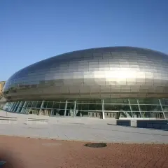 El moderno Palacio de Deportes Santander, con su diseño futurista y su cubierta plateada, se alza bajo un cielo azul.