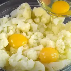 Do miski z kalafiorem dodawane są jajka. Pyszny obiad z kalafiorem w przygotowaniu.