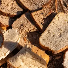 Stare kromki chleba, niektóre z ziarnami, leżą na ziemi, tworząc naturalny nawóz z chleba.