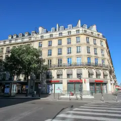 Elegancka kamienica przy rue de Rivoli w Paryżu, z markizami nad oknami i sklepem Foot Locker na parterze.