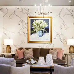 A living room with traditional interior design, featuring a floral wallpaper, a painting of tulips, a brown sofa, and plush armchairs.
