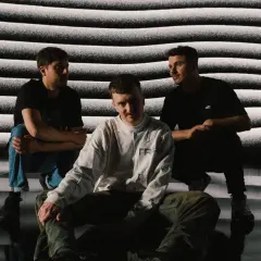 Drei Männer vor einer Wellenmuster-Projektion. Ein Konzert-Moment, der an das Steintor erinnert, mit einem Hauch von Herrenchor-Atmosphäre.