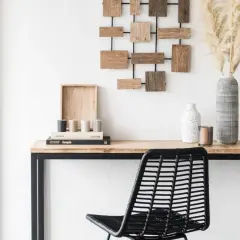 Un bureau en bois avec une chaise noire, des livres, des vases et une décoration murale. Idéal pour apprendre comment décalquer sur du bois.
