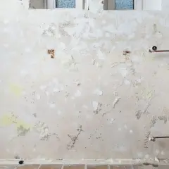 Feuchte Wand mit abblätterndem Putz, Salpeter-Ausblühungen und Kupferrohren. Was ist Salpeter? Ein Salz, das bei Feuchtigkeit entsteht.