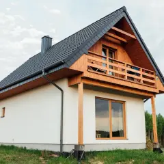 Nowoczesny dom kanadyjski, białe ściany, drewniana weranda i dach. Projekty domów tego typu są popularne.