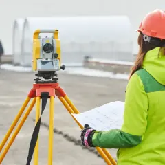 Geodetka z mapą przy tachimetrze. Czy geodeta musi powiadomić sąsiadów o pracach?