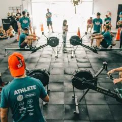 Ludzie trenują na wioślarzach w sali treningowej. Szukasz crossfit Warszawa gdzie? To miejsce jest idealne!