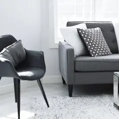 Nowoczesny salon z szarą kanapą i fotelem. Idealne miejsce na relaks po całym dniu, jak i do planowania, co obejmuje kredyt na remont mieszkania.