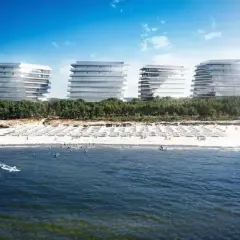 Nowoczesne budynki nad plażą w Międzyzdrojach, gdzie widać kitesurfera na falach.