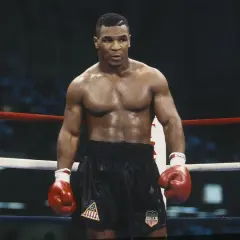 Mike Tyson in the ring, ready to fight. His intense gaze and powerful physique embody the spirit of how to fight like Mike Tyson.