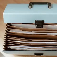 Akta z dokumentami, gotowe do wysłania pocztą. Widać segregatory i papiery.