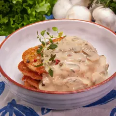 Placki ziemniaczane z kremowym sosem pieczarkowym, udekorowane ziołami. Zastanawiasz się, ile może stać sos pieczarkowy w lodówce?
