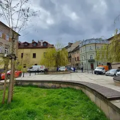 Plac rybny Lublin z kolorowymi kamienicami, zielenią i zaparkowanymi samochodami.