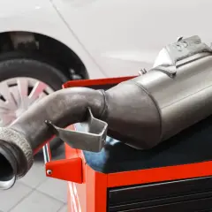 Filtr DPF na czerwonej skrzynce narzędziowej, obok koła samochodu. Zastanawiasz się, ile popiołu w dpf?