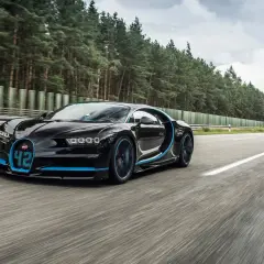 Czarny Bugatti Chiron z niebieskimi akcentami pędzi po pustej drodze, osiągając prędkość 500 km/h.
