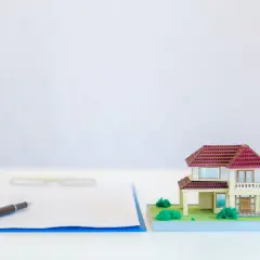 Wniosek KW-wpis wzór wypełnienia spadek. Miniatura domu obok dokumentów i długopisu sugeruje formalności związane z dziedziczeniem nieruchomości.