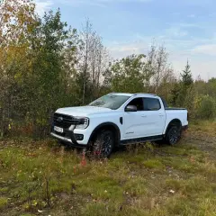 Vit Ford Ranger Wildtrak står parkerad vid en skogsväg. Kanske ett litet problem med terrängen?
