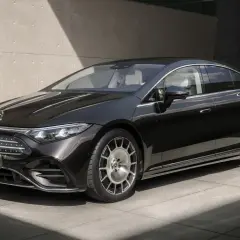Elegancki, czarny Mercedes-Benz EQS, lśniący w słońcu, z charakterystycznym grillem i felgami.