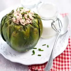 Artichaut farci au thon, garni de ciboulette. Une idée de recette artichaut simple et savoureuse, servie avec une sauce crémeuse.