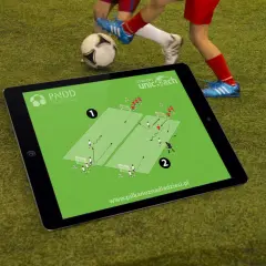 Tablet z planem treningowym do piłki nożnej na 2 osoby. Dzieci ćwiczą na boisku.