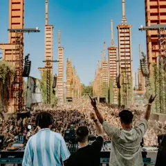 DJ set al futur festival torino, con una folla immensa e torri arancioni che si ergono verso il cielo.