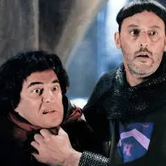 Goście, goście! Obsada filmu w średniowiecznych strojach, jeden z nich groźnie patrzy, drugi ma rękę na jego szyi.