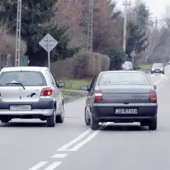 Srebrny samochód wyprzedza ciemny, jadący po tej samej drodze. Wymijanie i omijanie to kluczowe manewry na drodze.
