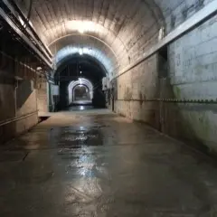 Wnętrze tunelu zapory Solina. Zwiedzanie cennik. Wilgotna posadzka, betonowe ściany, łukowe sklepienie z instalacjami.