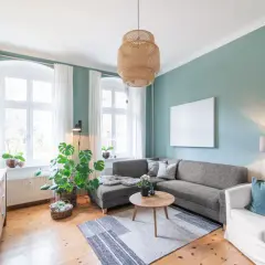 Gemütliches Wohnzimmer mit Sofa, Sessel und Holzboden. Pflanzen und natürliche Materialien schaffen eine harmonische Feng Shui Atmosphäre.