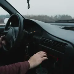 Ręka kierowcy szuka kodu do radia Renault, by włączyć ulubioną muzykę podczas podróży.