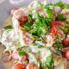 Cremiges low carb lachs Gericht mit Zucchini-Nudeln, Kirschtomaten und frischem Basilikum.