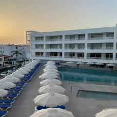 Hotel moderno con piscina y tumbonas, vistas al mar y al atardecer. El azul mar de Lagos de César invita al descanso.