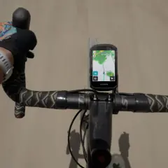 Rowerzysta z rękami w rękawiczkach na kierownicy, na której zamontowany jest Garmin z mapą. Zastanawiasz się, jaki Garmin wybrać?
