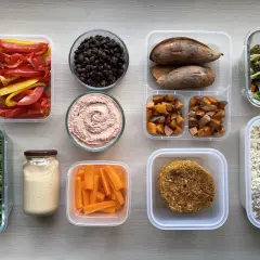 Healthy Japanese bento box ideas for adults: rice, veggie patties, roasted sweet potatoes, carrots, hummus, black beans, and fresh greens.